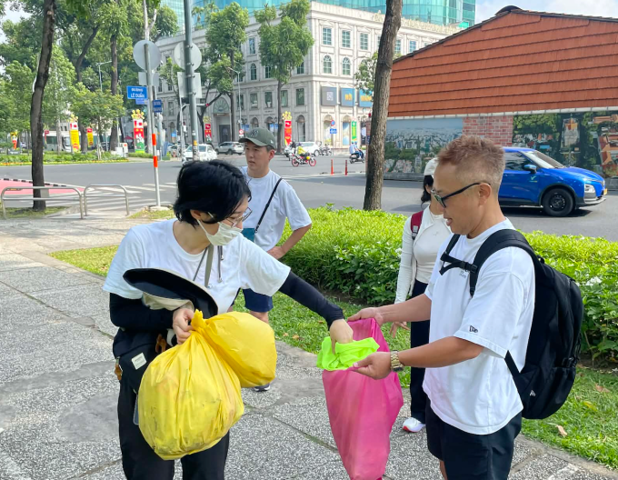 Anh Kenta Fuji cùng tình nguyện viên thu dọn rác ở Công viên 30/4, TP HCM, sáng 29/3. Ảnh: Ngọc Ngân