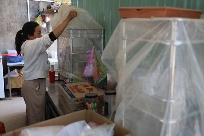 Chị Hương dùng nylon phủ kín giá để ly, chén ngăn bụi. Ảnh: Trần Hóa