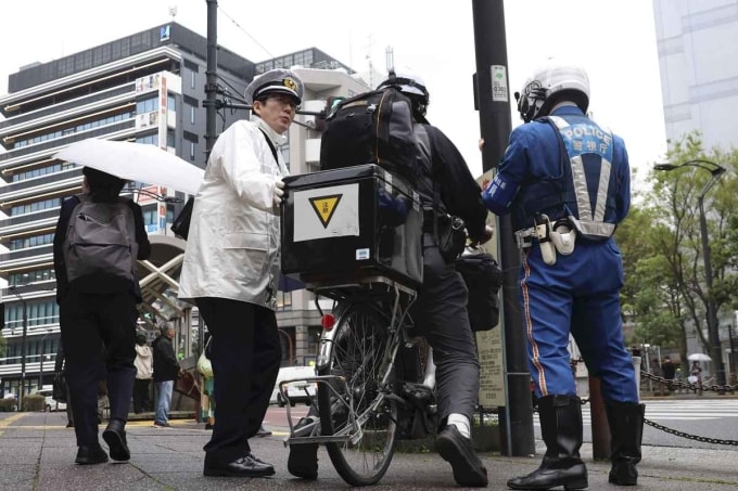 Các cảnh sát giải thích hệ thống phạt tại chỗ vé xanh cho một người đi xe đạp trên đường phố ở quận Kita, Tokyo. Ảnh: The Yomiuri Shimbun