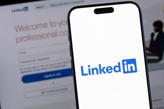 Logo LinkedIn trên smartphone và website nền tảng này phía sau. Ảnh: Socialflyny