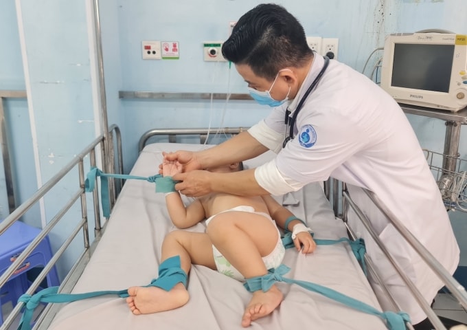 Trẻ tay chân miệng nặng điều trị tại bệnh viện Nhi đồng 1, được cố định tay chân vào giường để tránh kích thích. Ảnh: Lê Phương