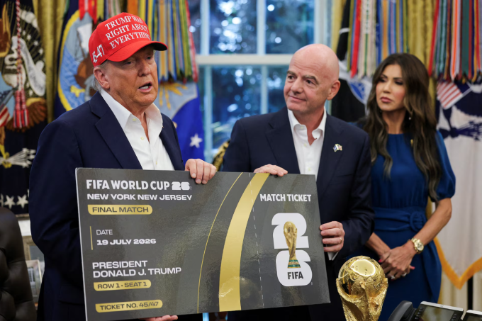 Tổng thống Mỹ Donald Trump và Chủ tịch FIFA Gianni Infantino cầm vé trận chung kết World Cup 2026, với Bộ trưởng An ninh Nội địa Mỹ Kristi Noem đứng phía sau tại Phòng Bầu dục, Nhà Trắng, Washington D.C., ngày 22/8/2025. Ảnh: Reuters