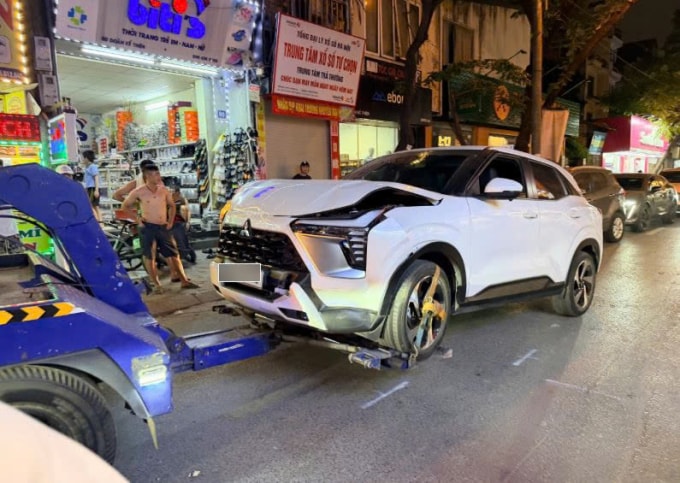 Cảnh sát cẩu chiếc xe gây tai nạn rời khỏi hiện trường. Ảnh: Việt An