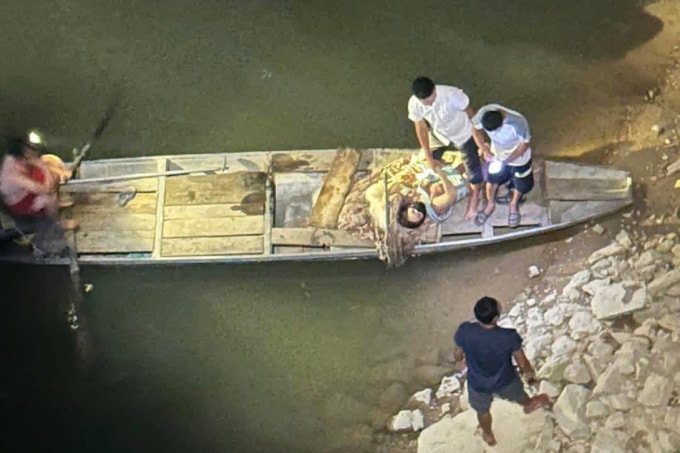 Người dân dùng thuyền gỗ hỗ trợ đưa hai nạn nhân vào bờ, tối 12/4. Ảnh: Hùng Lê