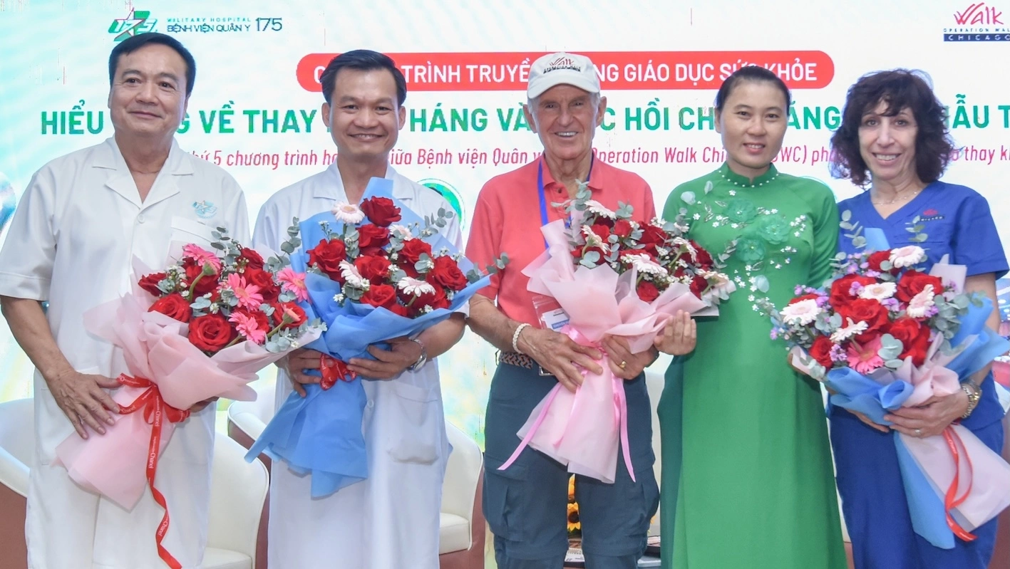 Chị Thúy Liễu (mặc áo dài xanh) tặng hoa cảm ơn bác sĩ Bệnh viện Quân y 175 và Tổ chức Operation Walk Chicago (Mỹ) vào chiều 13-4