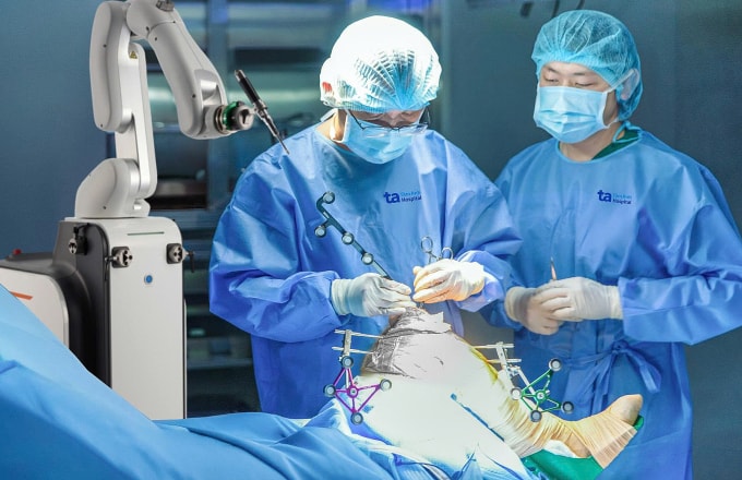 Bác sĩ Bảo (trái) thực hiện thay khớp gối cho người bệnh dưới sự hỗ trợ của robot Cuvis-Joint. Ảnh: Bệnh viện Đa khoa Tâm Anh