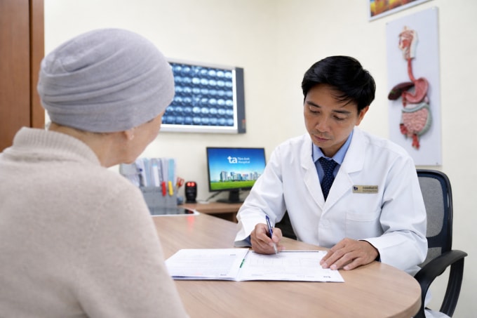 Bác sĩ Thái đọc kết quả của bà Hương trong ngày tái khám. Ảnh: Bệnh viện Đa khoa Tâm Anh