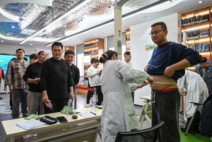 Người dân địa phương là nam giới xếp hàng đo vòng bụng, chiều cao cân nặng trong chiến dịch đổi mỡ lấy thịt bò tại một trung tâm cộng đồng ở thành phố Vô Tích, tỉnh Giang Tô, ngày 23/3. Ảnh: AFP