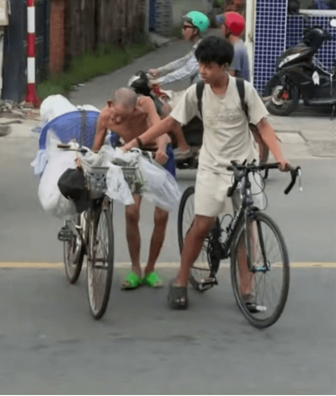 Cậu bé giúp ông cụ đẩy xe ve chai qua dòng xe cộ đông đúc