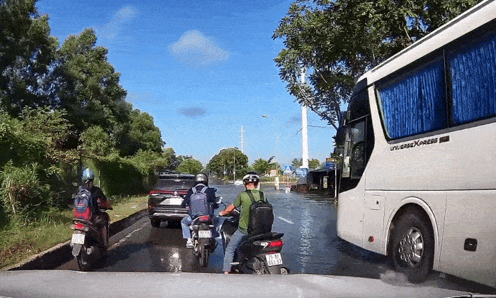 Xe khách bất chấp lao qua đường ngập, hất nước vào xe máy